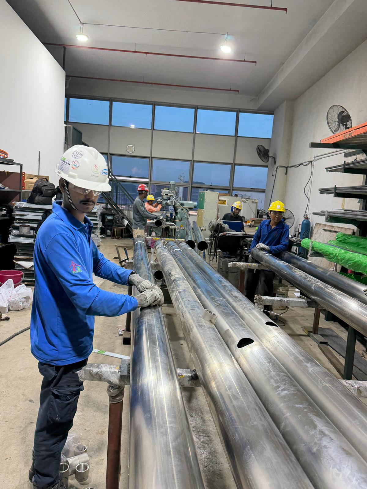Fabrication team preparing steel pipe assemblies